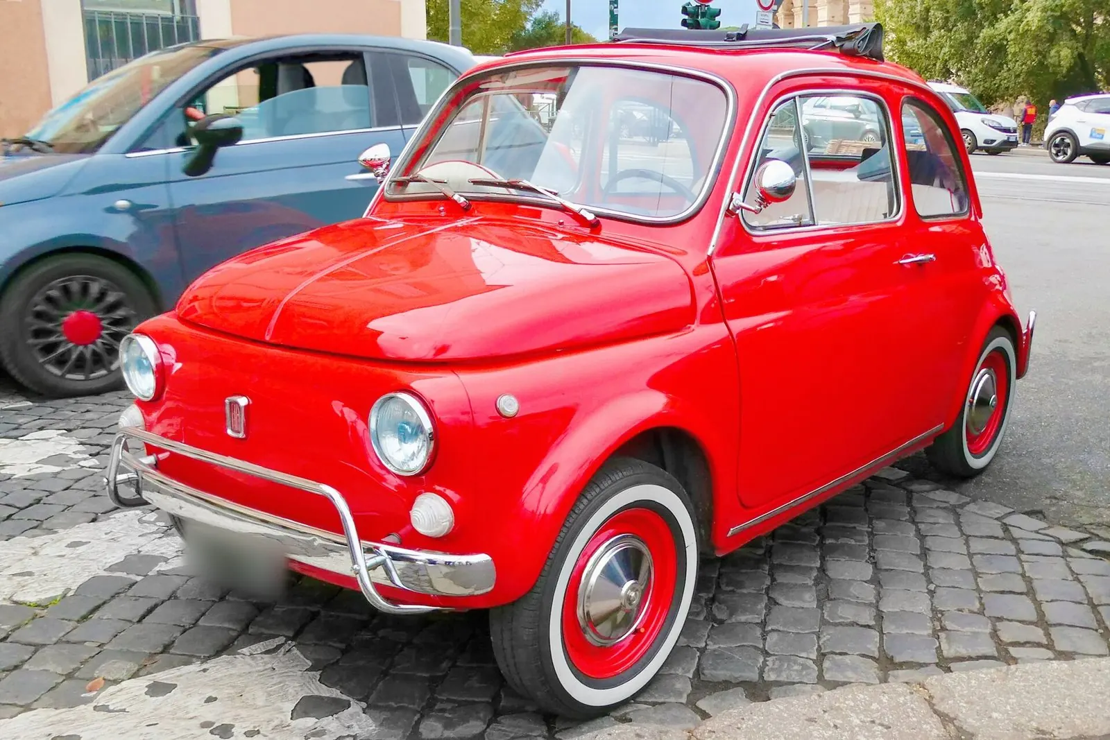 Fiat 500 rouge des années 60 aux jantes blanches, garée sur les pavés de Rome