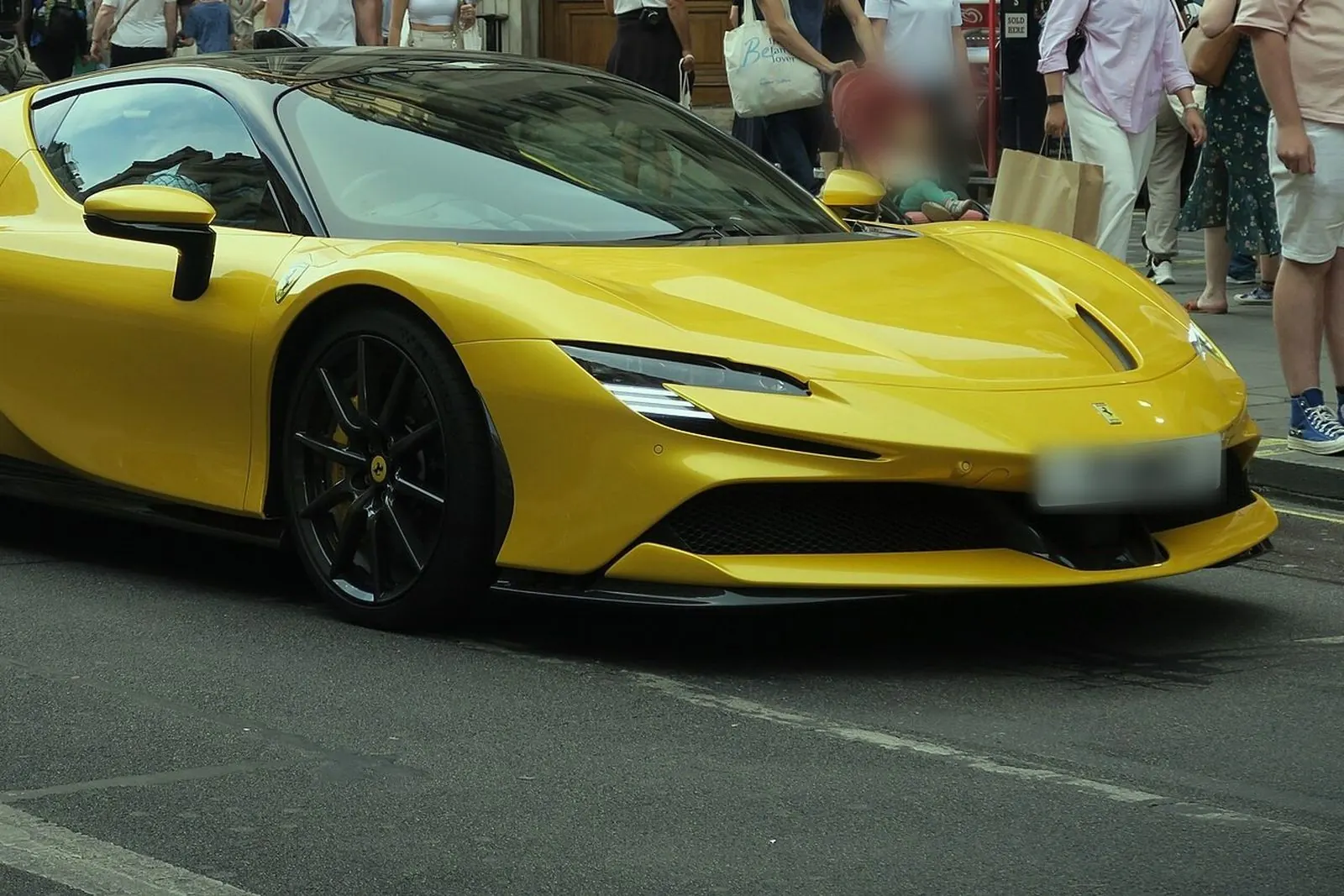 Ferrari SF90 Stradale jaune dans une rue commerçante